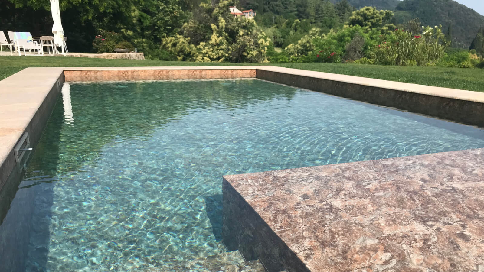 Piscina rettangolare con bordo in pietra e verde, progetto di spazio esterno